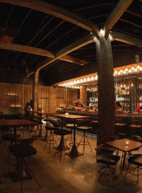 This image shows Drinking & Healing, a speakeasy cocktail bar in Ho Chi Minh City with a chic and modern vibe. The interior features dim lighting, stylish decor, and a cozy seating arrangement. A bartender is seen mixing a unique cocktail at the counter, showcasing the bar’s focus on creativity and quality. Patrons are seated in small groups, enjoying their drinks in a calm and intimate atmosphere. The overall vibe is trendy yet relaxed, ideal for quiet evenings.