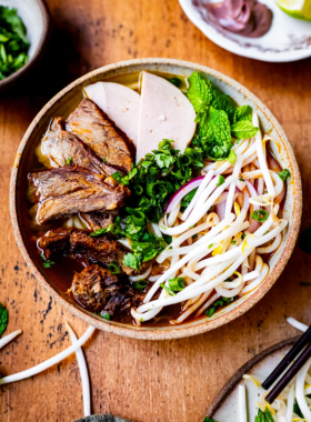 This image shows that Bun Bo Hue is a signature Vietnamese noodle soup from Hue, featuring a flavorful and aromatic broth with tender beef slices, rice noodles, and fresh herbs. The image captures a steaming bowl served with lime, chili, and bean sprouts on the side, which adds more flavor. It reflects the richness and authenticity of Hue’s culinary heritage, making this dish a favorite among food lovers and a must-try when visiting the city.