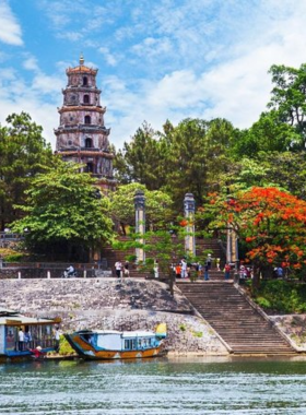 This image shows that Thien Mu Pagoda is a famous spiritual site in Hue, Vietnam, situated on a hill overlooking the Perfume River. The iconic seven-story pagoda, surrounded by lush greenery, is captured in the image, reflecting its serene beauty. Visitors can also see the calm and scenic environment, making this a perfect spot for reflection and photography. The peaceful setting highlights the importance of this pagoda as a symbol of Hue’s cultural and spiritual heritage.