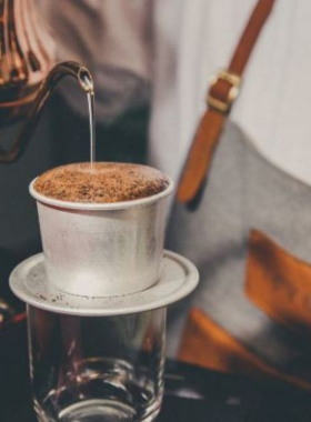 This image shows Salt Coffee, a unique and Instagram-worthy cafe in Hue. The image focuses on a cup of salted coffee, the cafe's signature drink, alongside a delicious snack. The cozy vibe of the cafe is highlighted, offering a comfortable space for people to relax and enjoy their beverages. Salt Coffee is one of the most popular spots for coffee lovers, known for its innovative flavors and friendly service. It's a perfect place to unwind after a busy day of exploring the city.