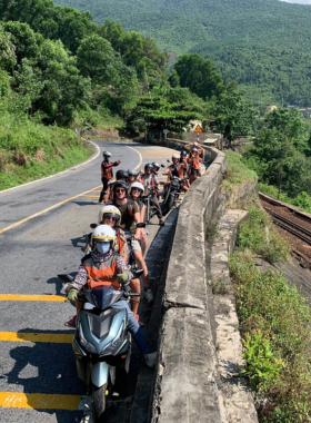 This image shows a group of travelers on motorbikes exploring the countryside around Hue, Vietnam, as part of a Le Family Rider tour. The winding road is surrounded by lush green rice fields, small villages, and scenic landscapes. The guides are seen leading the group, sharing insights about local culture and history. The image captures the adventurous and immersive experience of this motorbike tour, offering travelers a unique way to connect with Vietnam’s rural beauty and heritage.This image shows a group of travelers on motorbikes exploring the countryside around Hue, Vietnam, as part of a Le Family Rider tour. The winding road is surrounded by lush green rice fields, small villages, and scenic landscapes. The guides are seen leading the group, sharing insights about local culture and history. The image captures the adventurous and immersive experience of this motorbike tour, offering travelers a unique way to connect with Vietnam’s rural beauty and heritage.