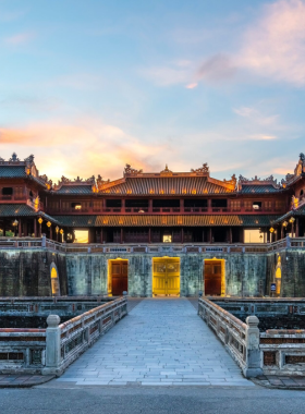 This image shows the Hue Citadel, a UNESCO World Heritage site in Vietnam. The sprawling complex features grand palaces, temples, and traditional Vietnamese architecture, surrounded by a vast moat. The iconic Noon Gate is prominently visible, showcasing its intricate design and historical significance. Visitors can be seen exploring the pathways, soaking in the rich imperial history. The lush gardens and ornate structures add to the timeless charm of this historic site, making it a must-visit destination for culture and history enthusiasts.