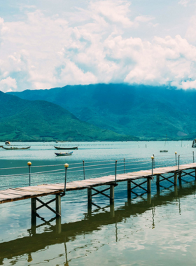 This image shows the peaceful waters of Lap An Lagoon reflecting the surrounding mountains and blue skies. Oyster farms can be seen in the foreground, showcasing the local livelihoods. The tranquil setting is enhanced by the soft lighting of the late afternoon, making the lagoon look magical. The image captures the natural charm of Lap An Lagoon, a perfect destination for relaxation and stunning photography. It highlights the lagoon’s pristine beauty and its role in the lives of local communities.