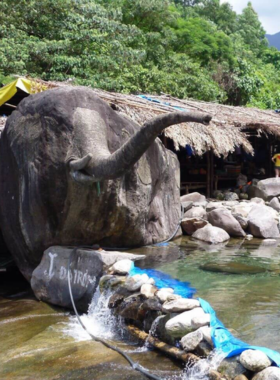 This image shows the crystal-clear natural pools of Elephant Springs surrounded by large boulders and lush greenery. Visitors can be seen enjoying the cool waters and relaxing in the peaceful environment. The cascading waterfall adds a dynamic element to the scene, making it a refreshing spot for swimming and photography. The image captures the adventurous and tranquil essence of Elephant Springs, showcasing it as a hidden gem for nature lovers near Hue.