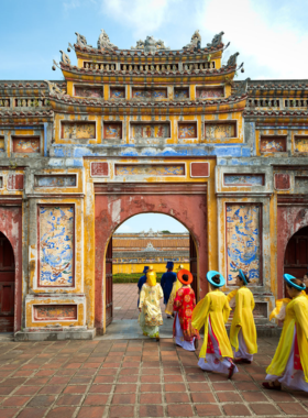 This image shows the beautiful gardens and historic architecture of the Hue Imperial City. The ancient walls are adorned with intricate carvings, while vibrant flowers and greenery enhance the setting. Visitors can be seen exploring the pathways, surrounded by a serene and cultural atmosphere. The image highlights the blend of nature and history at this UNESCO World Heritage site, making it a must-visit for anyone exploring Hue. It showcases the timeless charm and significance of the Imperial City.