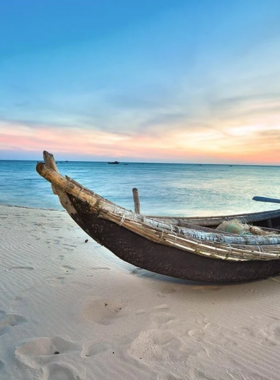 This image shows the golden sands and calm waves of Thuan An Beach during sunset. The sky is painted in warm shades of orange and pink, reflecting on the gentle waters. A few people can be seen strolling along the shore, enjoying the peaceful ambiance. The beach looks pristine and inviting, perfect for relaxation or a quiet escape. The image highlights the natural beauty and tranquil atmosphere of Thuan An Beach, a coastal gem near Hue.