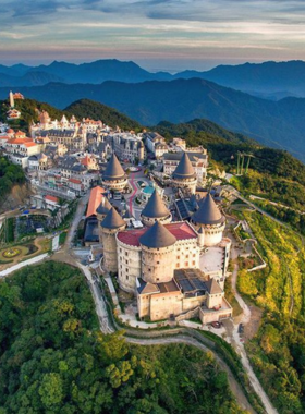 This image shows the famous Golden Bridge at Ba Na Hills, with its hands made of stone holding up the bridge. The bridge is set against a backdrop of lush mountains, offering a stunning panoramic view. Visitors can be seen walking across the bridge, taking in the incredible views. The image captures the magical atmosphere of Ba Na Hills, where French architecture, colorful gardens, and breathtaking landscapes create an unforgettable experience.