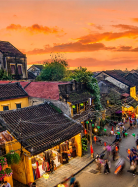 This image shows the charming ancient streets of Hoi An, lined with traditional lanterns and historic architecture. The streets are bustling with life, with tourists and locals enjoying the atmosphere. You can see people visiting traditional workshops and exploring the town's rich cultural heritage. At night, the lanterns light up, creating a dreamy and magical ambiance. The image captures the timeless beauty and cultural richness of Hoi An, making it a perfect day trip from Da Nang.