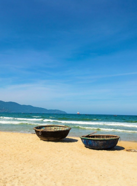 This image shows Phuoc My Beach in Da Nang, Vietnam. The beach offers a calm environment with soft sands and clear blue waters. In the image, people can be seen swimming, relaxing under umbrellas, and enjoying the peaceful setting. The beach is perfect for those who want a quieter experience, away from the bustling crowds. The background highlights the natural beauty of the coastline, with lush hills and clean, inviting waters that make Phuoc My a great beach destination.