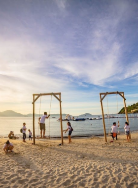 This image shows Tien Sa Beach, located on the outskirts of Da Nang, Vietnam. The beach is surrounded by lush hills, offering a more serene and peaceful atmosphere compared to more popular beaches. The image highlights the crystal-clear water, perfect for swimming or enjoying nature. People can be seen strolling along the beach or sitting on the sand, soaking up the sun. Tien Sa Beach is a perfect spot for those looking for a quiet getaway, with its scenic beauty and relaxing ambiance.