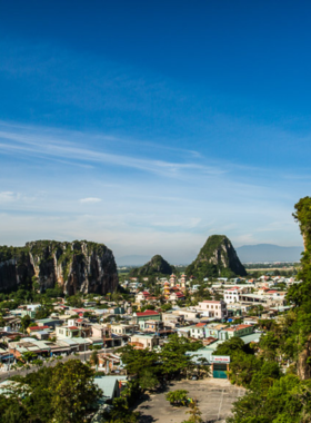 This image shows hikers exploring the Marble Mountains in Da Nang, Vietnam. The steep mountain trails lead to breathtaking panoramic views of the surrounding landscape, including the city, beaches, and nearby islands. People are seen walking through caves, passing by ancient temples and shrines, surrounded by lush greenery. The image captures both the spiritual and natural beauty of the mountains, making it an ideal destination for those seeking adventure, a connection to nature, and a little bit of history.