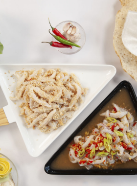 This image shows Nam O Fish Salad, a traditional dish from Da Nang, being served at a local eatery in Nam O village. The picture captures fresh fish marinated with lime, chili, and herbs, accompanied by rice paper and greens. Diners are seen wrapping and enjoying the dish, which represents the simplicity and authenticity of Vietnamese coastal cuisine. The rustic surroundings highlight the cultural essence of the village.