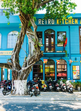 This image shows Retro Kitchen and Bar, a café-bar hybrid in Da Nang. The photo highlights the eclectic interiors with modern lighting, cozy seating, and a mix of café and bar elements. A table displays a creamy latte alongside a handcrafted cocktail, representing the venue’s diverse offerings. Guests are seen enjoying food and drinks in a lively yet relaxed atmosphere. The space transitions effortlessly from a day café to a vibrant evening bar.