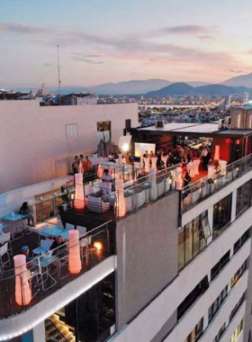 This image shows The Top Bar, located at the A La Carte Hotel in Da Nang. The bar features an infinity pool with a stunning view of the coastline and city. The setting is serene, with people enjoying poolside drinks, soft lighting, and a cool ocean breeze. The casual yet luxurious vibe makes it a unique spot for those who want to relax during the day or experience a glamorous evening under the stars.