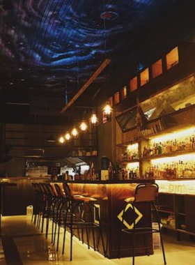 This image shows The Craftsman Cocktail Bar, a hidden speakeasy-style bar in Da Nang. The interior is vintage and inviting, with dim lighting, leather chairs, and shelves of premium spirits. A bartender is seen creating a custom cocktail with precision. The cozy atmosphere is perfect for small groups or solo visitors seeking a quiet escape from the city’s hustle. The bar exudes charm and sophistication, ideal for cocktail lovers and explorers of unique venues.