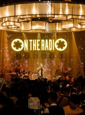 This image shows On the Radio Bar, a cozy live music bar in Da Nang. The setting includes a stage where local bands perform, surrounded by an intimate crowd enjoying the show. The bar’s warm lighting, rustic decor, and friendly vibe make it a welcoming space for music lovers. Guests are seen clapping and tapping along to the rhythms, creating a lively yet comfortable atmosphere ideal for an authentic nightlife experience.