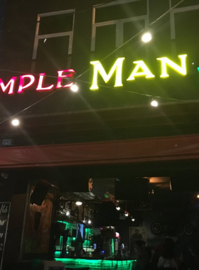 This image shows Simple Man Bar, a charming and cozy bar in Da Nang. The setting features a small, warmly lit space with comfortable seating and minimalist decor. Guests are seen chatting over drinks in a relaxed environment. The bar exudes a homely vibe, making it an inviting place for both locals and travelers seeking a low-key, intimate spot to unwind. The simplicity and warmth of the bar make it stand out for casual evening hangouts.