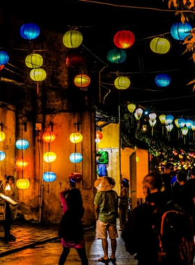 This image shows the magical atmosphere of Hoi An’s Lantern Festival, where the streets light up with vibrant lanterns during the full moon. The image captures the lanterns floating along the Thu Bon River, creating a serene and nostalgic ambiance. Locals and tourists enjoy traditional snacks, and visitors can release floating lanterns for good luck. The festival brings a unique sense of warmth and nostalgia, immersing visitors in a timeless experience under the glow of colorful lanterns.