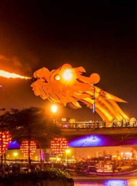 This image shows the dramatic Dragon Bridge in Da Nang, illuminated at night during its fire and water show. The dragon-shaped bridge breathes fire and releases water, creating a mesmerizing spectacle for onlookers. The vibrant lights add to the excitement of the show, making it a fun and unique attraction in the city. The image captures the energy and innovation of the bridge, showcasing Da Nang’s modern spirit while providing entertainment for both locals and tourists.