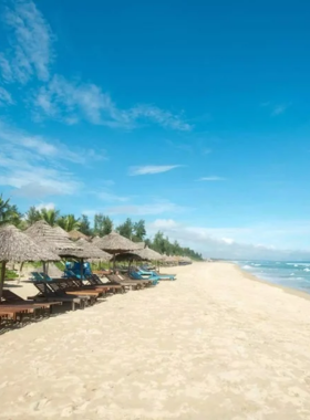 This image shows the stunning sunrise at An Bang Beach in Hoi An. The beach is known for its soft white sands and calm, relaxing atmosphere. Early morning hues of orange and pink fill the sky, creating a serene environment perfect for walking along the shore. In the background, a few locals and tourists are seen enjoying the quiet beauty of the beach. Beachside cafes and fresh coconut water are other highlights of this popular spot for relaxation.