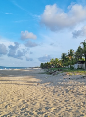 This image shows the serene and untouched beauty of Ha My Beach in Hoi An. The soft white sand stretches far, meeting the clear blue sea under a vibrant sky. A couple of tourists are seen sitting on towels, enjoying the peaceful and uncrowded surroundings. Ha My Beach is a hidden gem, perfect for those seeking solitude and an off-the-beaten-path experience. The natural beauty and quiet atmosphere make it a favorite among photographers and beach lovers.