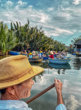 This image shows a family enjoying a Long Phu Eco Tour in Hoi An. A small wooden boat navigates through a picturesque river surrounded by lush greenery. The guide, a local expert, explains the area’s cultural and natural significance. In the background, another group is learning traditional fishing techniques. This eco-tour provides a hands-on, immersive experience that connects visitors to local traditions and the beauty of Vietnam’s countryside, making it a perfect family-friendly activity.