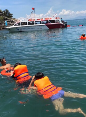 This image shows a luxurious catamaran used by Tiger Fish Divers for snorkeling and diving tours around Hoi An’s Cham Islands. The scene features a group of divers in vibrant wetsuits exploring the colorful coral reefs beneath crystal-clear waters. The spacious catamaran is docked nearby, with tourists relaxing on the deck, enjoying the sun. This activity offers a mix of adventure and relaxation, making it a perfect way to explore the marine biodiversity in style and comfort.