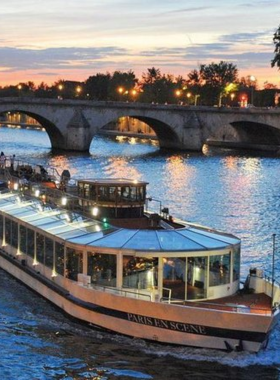 This image shows a scenic Seine River cruise, with a boat gliding peacefully along the water. On either side, the grand landmarks of Paris, like the Eiffel Tower and Notre-Dame Cathedral, can be seen towering over the city. The sky is clear, and the reflection of the buildings on the river adds to the charm of the scene. A Seine River cruise is a fantastic way to experience Paris from a different perspective, offering unforgettable views of the city’s most famous attractions.