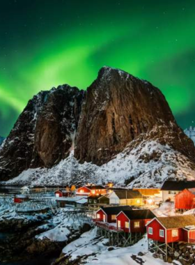 This image shows the vibrant Northern Lights, or aurora borealis, lighting up the night sky over Tromsø, Norway. The display features green, purple, and pink hues dancing across the Arctic sky, creating a mesmerizing and magical atmosphere. The snowy landscape below adds to the breathtaking view, making it an unforgettable natural wonder.