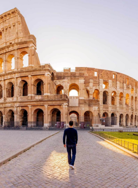 This image shows the ancient Colosseum in Rome, Italy, a magnificent amphitheater steeped in history. The partially preserved structure reveals its grand arches and layered seating, giving a glimpse into the Roman era. Visitors explore the underground chambers and marvel at the massive scale of this historical landmark, once the site of gladiator battles and public spectacles.