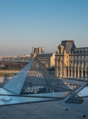 This image shows the iconic Louvre Museum in Paris, France, with its modern glass pyramid entrance and historic palace buildings. Inside, visitors admire masterpieces like the Mona Lisa, Winged Victory of Samothrace, and countless other treasures spanning centuries of art and history. The museum is a haven for art enthusiasts from around the world.