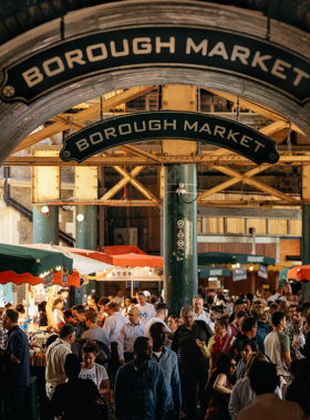 This image shows Borough Market, a vibrant and bustling food market in London offering a wide variety of delicious food from around the world. Visitors can explore a selection of street food, fresh produce, artisan goods, and specialty products. The market is a perfect place for food lovers to sample unique dishes and enjoy a lively atmosphere. Whether you're grabbing a quick snack or enjoying a full meal, Borough Market promises an unforgettable culinary experience in London.