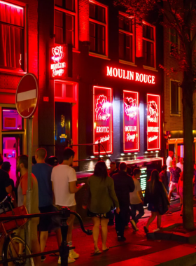 This image shows the bustling Red Light District of Amsterdam, known for its vibrant nightlife and historic charm. Visitors can stroll through the district, where centuries-old buildings and canals create a unique atmosphere. There are also hidden churches and museums, like the Museum of Prostitution, offering insights into the district’s cultural and social history. When visiting, it’s important to be respectful and mindful, as photography of workers is prohibited. It’s an area with a rich history that can be explored on foot.