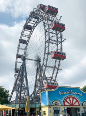 This image shows the Giant Ferris Wheel at the Prater Park in Vienna, an iconic landmark offering sweeping views of the city. Standing 65 meters tall, the wheel is a popular attraction for both tourists and locals. Visitors can enjoy a ride in the enclosed cabins for a unique perspective of Vienna's skyline, including the Danube River and the historic city center. The Ferris wheel is especially beautiful at night when the city is illuminated by lights.