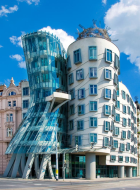 This image shows the Dancing House in Prague, an iconic example of modern architecture. Designed to resemble a pair of dancers, the building stands out against the backdrop of the city’s historic structures. It is one of the most recognizable landmarks in Prague, offering visitors a glimpse of the city’s contemporary architectural scene. The building houses offices, a restaurant, and a rooftop terrace, making it a popular spot to visit for a unique photo or simply to admire its innovative design.