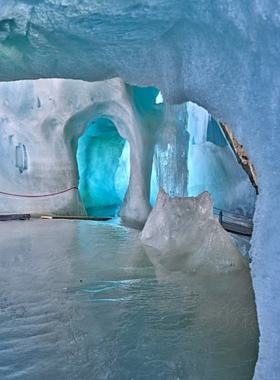 This image shows the Eisriesenwelt Ice Caves, the largest ice cave system in the world, located in Werfen, Austria. Visitors can explore surreal ice formations, from frozen waterfalls to intricate ice sculptures, during a guided tour through the caves. The icy tunnels offer a magical and otherworldly experience, with the surrounding Alpine landscapes adding to the sense of adventure. A visit to these caves is a must for nature lovers and those seeking a unique adventure.