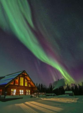 This image shows the mesmerizing Northern Lights, also known as the Aurora Borealis, dancing across the night sky in Yukon, Canada. Bright green, blue, and purple lights swirl above the snow-covered landscape. The phenomenon is caused by solar particles interacting with Earth's atmosphere, creating this magical glow. The cold winter nights provide the best conditions for viewing. People watch in awe as the lights move like waves across the sky. This breathtaking sight is one of nature’s most incredible displays, attracting travelers from around the world.