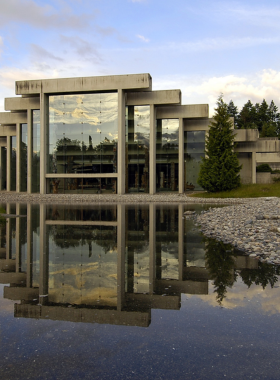 This image shows the Museum of Anthropology in Vancouver, a cultural treasure that showcases Canada’s Indigenous heritage. The museum’s entrance features towering wooden totem poles, intricately carved with traditional designs and symbols. Inside, visitors explore glass cases filled with Indigenous artifacts, including masks, tools, and pottery. The museum’s architecture blends natural light with wood and stone, creating a warm and inviting atmosphere. The exhibits provide deep insights into the history, traditions, and artistry of the First Nations people. Visitors can see life-sized canoes, woven baskets, and ceremonial clothing, each telling a unique story of Canada’s past. Outside the museum, the lush green surroundings complement the historical significance of the artifacts. The Museum of Anthropology is a must-visit for anyone wanting to understand and appreciate the rich Indigenous culture of Canada, making it an educational and eye-opening experience for travelers and history lovers alike.