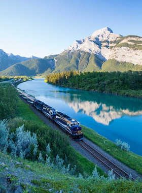 This image shows the luxurious Rocky Mountaineer train gliding through the Canadian Rockies, surrounded by breathtaking mountain landscapes. The train’s panoramic windows provide an uninterrupted view of the towering peaks, dense forests, and winding rivers. Inside, passengers relax in comfortable seats while enjoying gourmet meals and world-class service. The golden sunlight illuminates the mountains, casting a warm glow on the rugged terrain. The train crosses bridges, passes through tunnels, and winds around cliffs, offering a once-in-a-lifetime scenic journey. Along the way, travelers might spot wildlife such as bears, elk, and eagles. The Rocky Mountaineer is a bucket-list experience, combining luxury and adventure in a unique way. Whether you’re traveling from Vancouver to Banff or exploring other routes, this train ride provides a breathtaking, slow-paced way to soak in Canada’s stunning natural beauty, making it an unforgettable journey for nature and travel enthusiasts.