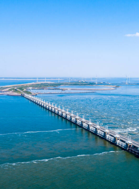 This image shows the Delta Works, a sophisticated system of dams, dikes, and storm surge barriers located in Zeeland, Netherlands. The Delta Works are one of the most remarkable engineering achievements in the world, designed to protect the Dutch coastline from flooding. The image showcases the scale and power of the engineering structures, with massive barriers and gates that control water levels. Visitors to the area can learn about the innovative flood prevention measures and their importance to Dutch society.