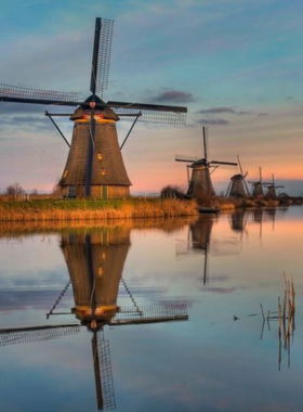 This image shows the picturesque windmills of Kinderdijk, a UNESCO World Heritage site in the Netherlands. The windmills, dating back to the 18th century, were originally used to manage water levels in the surrounding wetlands. The image captures the timeless beauty of the windmills standing tall against the backdrop of a serene Dutch landscape, making it one of the most iconic and photographed locations in the country. Kinderdijk is a must-visit for those interested in Dutch culture and history.