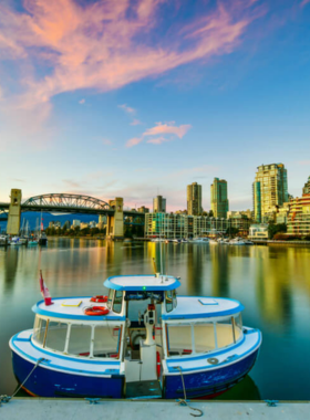 This image shows Granville Island, a lively cultural and food hub in Vancouver. The market is bustling with fresh produce, handcrafted goods, and local treats. People are seen shopping, dining at waterfront restaurants, and enjoying live street performances. Colorful artisan shops and art galleries line the streets, creating a vibrant and creative atmosphere. Boats and kayaks are docked nearby, adding to the island’s charm and making it a perfect spot to explore and enjoy local flavors.