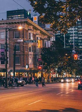 This image shows Robson Street, Vancouver’s busiest shopping district, lined with high-end boutiques, global fashion brands, and trendy stores. Shoppers are carrying bags, browsing window displays, and stopping at street cafés. The street is bustling with people, neon signs, and stylish storefronts. The vibrant city atmosphere, modern buildings, and luxury shopping options make this a must-visit destination for fashion lovers and those looking to experience Vancouver’s urban lifestyle.