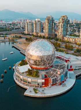 This image shows Science World, a futuristic geodesic dome in Vancouver filled with interactive exhibits. Families and children are engaging in hands-on experiments, learning about space, physics, and technology. Brightly colored displays, science demonstrations, and a large IMAX theater make the museum an exciting educational experience. Visitors are exploring different themed sections, making science fun and accessible for all ages. The unique dome-shaped architecture stands out in the city’s skyline.