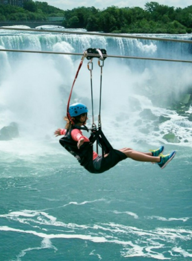 This image shows an excited tourist ziplining over the Niagara River, heading toward the Falls. The zipline provides a thrilling experience, offering a bird’s-eye view of the falls and surrounding landscape. The fast-paced ride gives adventurers a unique and adrenaline-pumping perspective of the falls, with the roar of the water and the mist in the air making it an unforgettable part of any Niagara Falls trip."