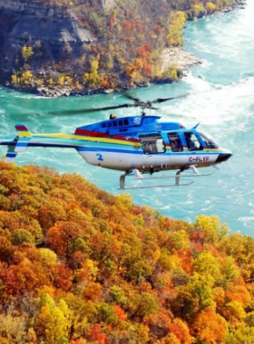 This image shows a helicopter flying over Niagara Falls, offering passengers breathtaking aerial views of the waterfall and the surrounding landscape. From the sky, tourists can marvel at the vastness of the falls and the beautiful green surroundings, capturing a stunning perspective that is impossible to experience from the ground. It’s a once-in-a-lifetime experience, offering a unique and thrilling way to see the iconic landmark."