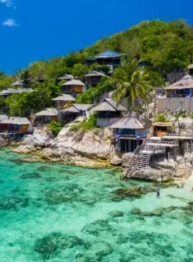 This image shows Jansom Bay in Koh Tao, a small yet stunning beach with calm, crystal-clear waters. Surrounded by lush green hills and smooth rocks, the beach offers a tranquil environment perfect for swimming and relaxing. Its peaceful charm makes it a hidden gem for visitors looking to escape the hustle and bustle.