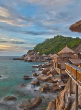 This image shows Sairee Beach, the most vibrant and active beach in Koh Tao. The beach is lined with palm trees, colorful beach bars, and lively restaurants. It offers a mix of water activities and vibrant nightlife, making it an ideal destination for both relaxation and adventure seekers. The golden sand and sunset views add to its allure.