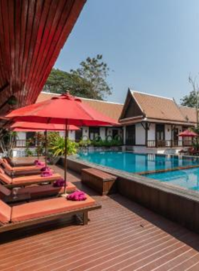 This image shows The Legendha Sukhothai, a riverside resort featuring beautiful wooden bungalows amidst a serene landscape. It offers a calm retreat with traditional Thai elements, a swimming pool, and a riverside restaurant serving local cuisine.