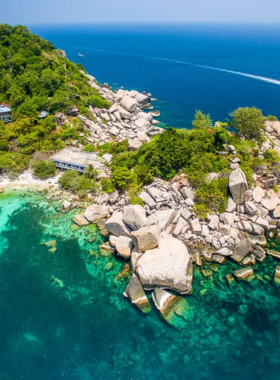 This image shows Laem Thian, a secluded beach in Koh Tao that offers an adventurous hike to reach. The clear waters, surrounded by rocky cliffs and dense vegetation, create a serene and untouched environment. The combination of hiking and relaxation makes it a rewarding destination for nature enthusiasts and adventure seekers.